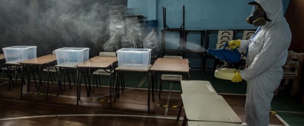 Un hombre sanitiza el gimnasio del Colegio Osorno College que funcionará como local de votación en las elecciones