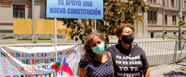 Mary y Érica, integrantes de las "Madres de la Constitución" posan delante del stand y de carteles alusivos a la Convención Constituyente.