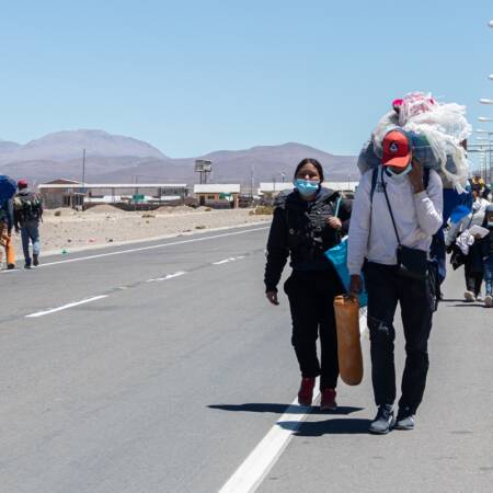 Familia de migrantes camina por un costado de la carretera.