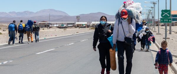 Familia de migrantes camina por un costado de la carretera.