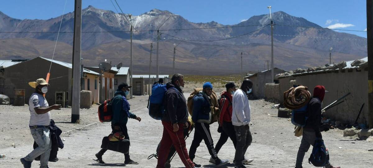 Un grupo de migrantes camina de izquierda a derecha por las calles de Iquique.