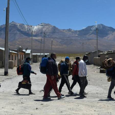 Un grupo de migrantes camina de izquierda a derecha por las calles de Iquique.