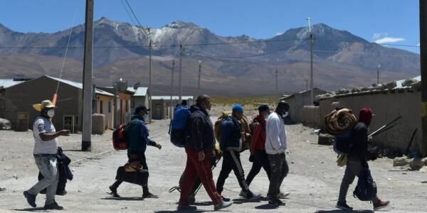 Un grupo de migrantes camina de izquierda a derecha por las calles de Iquique.
