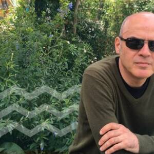 En la foto se puede ver al escritor Sergio Missana utilizando unos lentes de sol y un sweater verde.