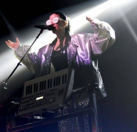 Javiera Mena vestida de color plata en un concierto en vivo