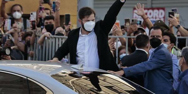 Gabriel Boric saliendo del auto presidencial y levantando la mano para saludar a la gente.
