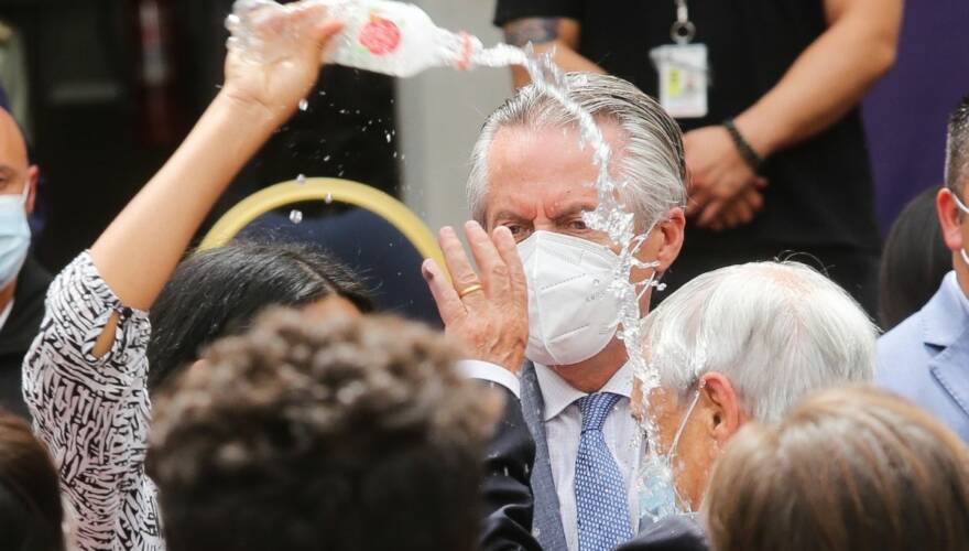 Audrey Burgos lanza agua al Presidente Sebastián Piñera luego de concluir la ceremonia de conmemoración de dos años del primer caso de Covid-19 en Chile.