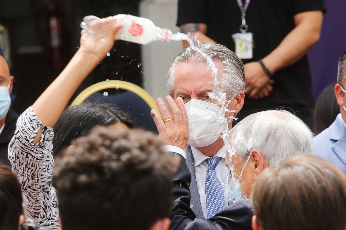 Audrey Burgos lanza agua al Presidente Sebastián Piñera luego de concluir la ceremonia de conmemoración de dos años del primer caso de Covid-19 en Chile.