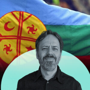 La imagen muestra a Julio Burdman frente a una bandera mapuche