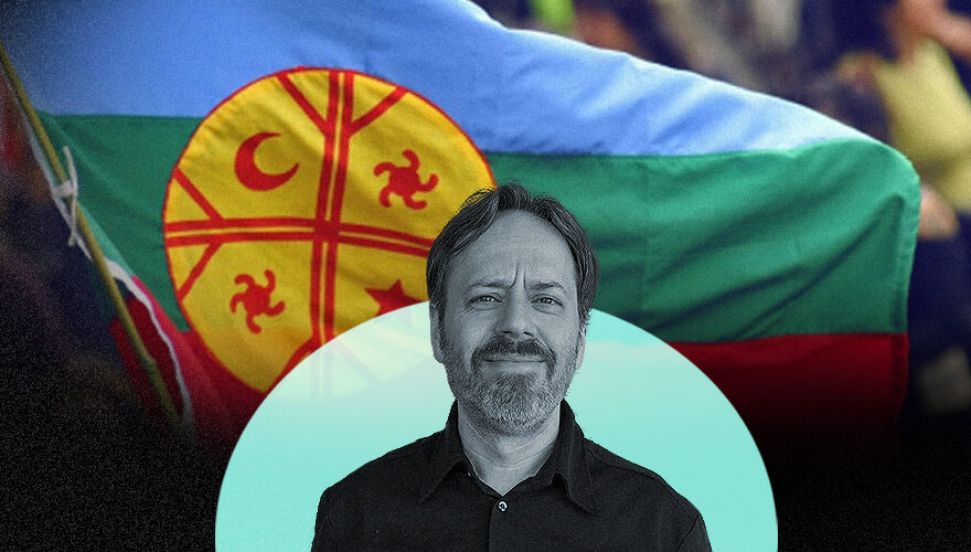 La imagen muestra a Julio Burdman frente a una bandera mapuche