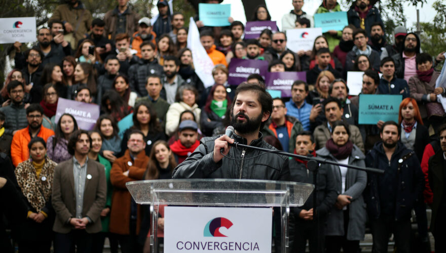 Gabriel Boric en un podio con un cartel de Convergencia Social y la militancia de ese partido detrás de él