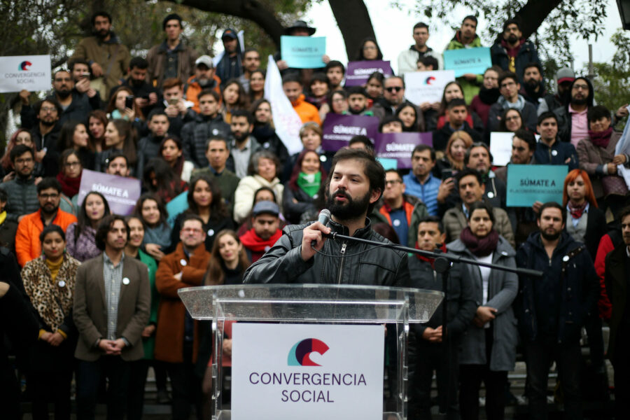Gabriel Boric en un podio con un cartel de Convergencia Social y la militancia de ese partido detrás de él