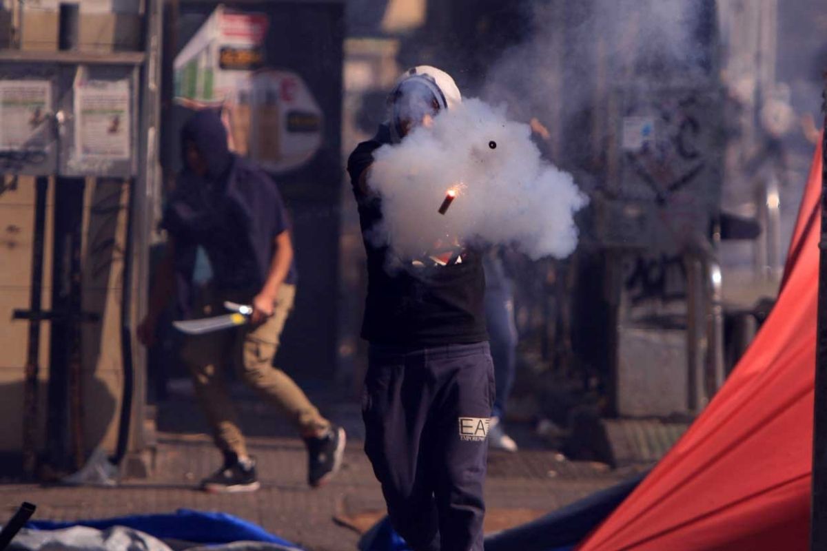 Un manifestante en el Barrio Meiggs dispara un arma a fogueo entre los toldos del comercio informal, en medio de los incidentes durante la marcha alterna del día del trabajador.
