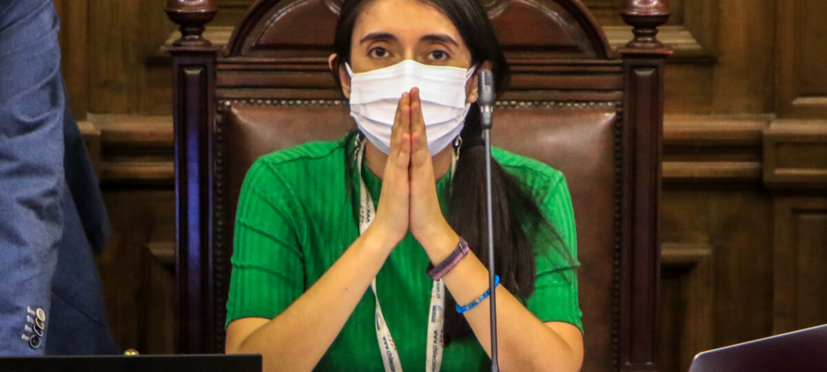 Maria Elisa Quinteros, sentada en el Pleno de la Convención Constitucional con sus codos apoyados en la mesa y sus manos juntas, como si estuviese rezando