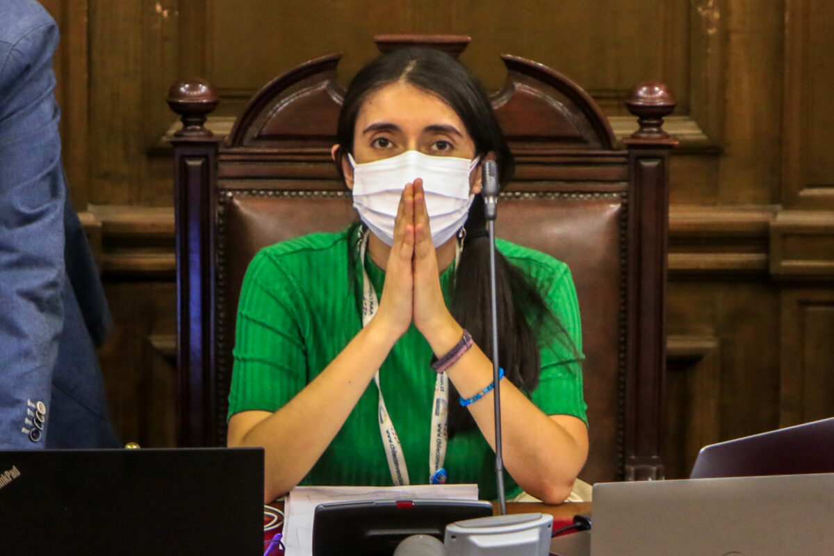 Maria Elisa Quinteros, sentada en el Pleno de la Convención Constitucional con sus codos apoyados en la mesa y sus manos juntas, como si estuviese rezando