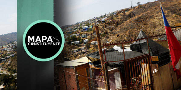 Un campamento de Valparaíso se encumbra entre los cerros. En primer plano, una vivienda construida con materiales livianos y una bandera chilena izada.