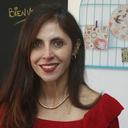 La abogada penalista María Elena Santibáñez mira hacia el frente, vestida con un vestido rojo.