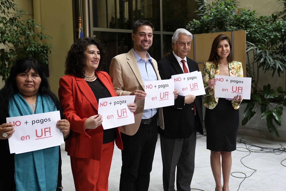 Parlamentarios del Partido Socialista sostienen letreros con el mensaje "No más pagos en UF".