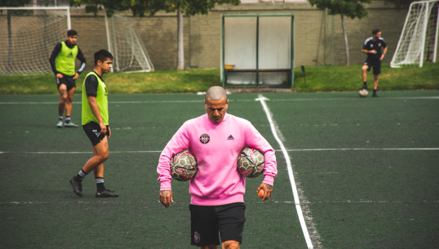 Jorge "Kike" Acuña, entrenador de Santiago City, con una pelota en cada brazo mientras dirige el entrenamiento del club que se prepara para enfrentar a Colo-Colo