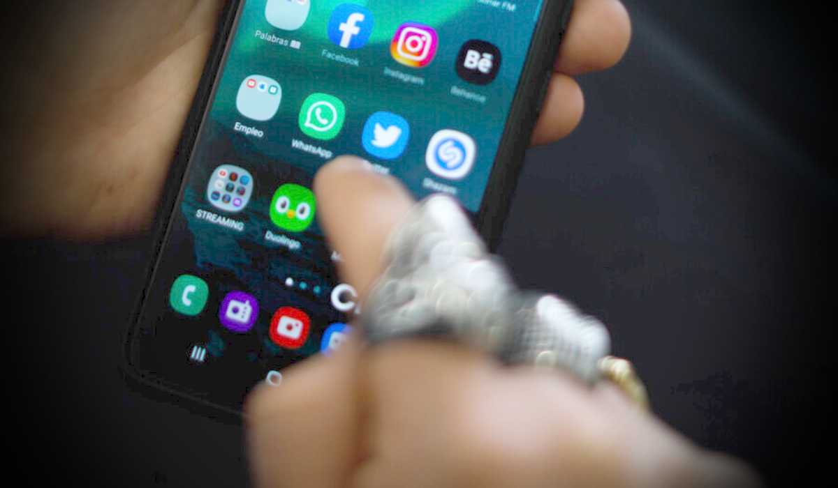 Manos sosteniendo un teléfono con la aplicación WhatsApp, donde circula una estafa.