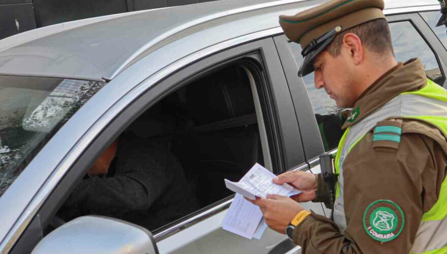 Funcionario de Carabineros de Chile fiscalizando a un conductor si tiene licencia de conducir