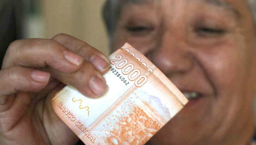 Mujer sonriendo con el dinero del Bono Invierno en la mano