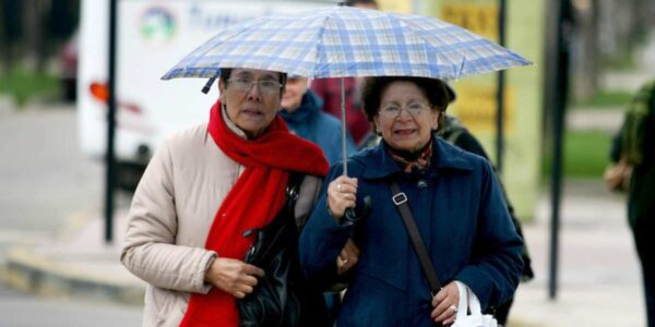 Mujeres caminando con paraguas por lluvia