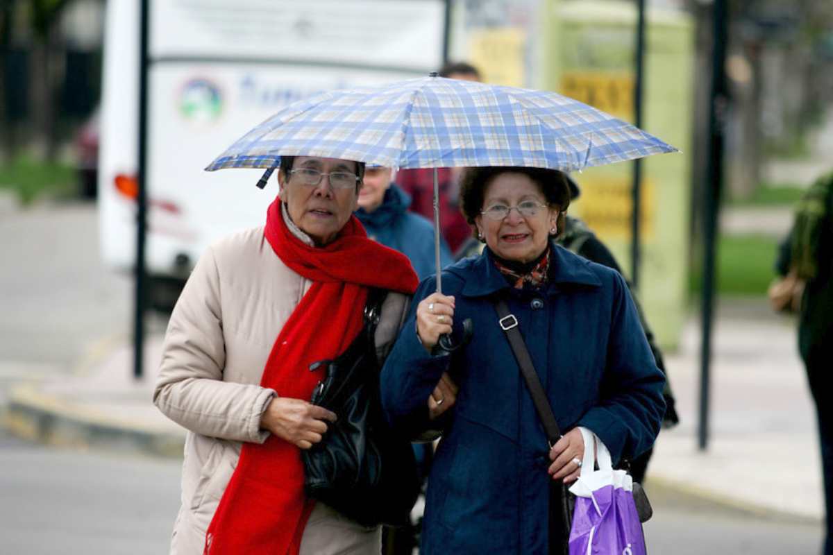 Mujeres caminando con paraguas por lluvia