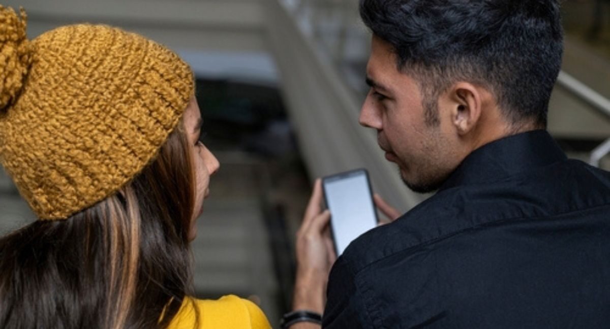 Dos personas viendo un teléfono Claro.