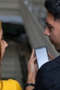 Dos personas viendo un teléfono Claro.