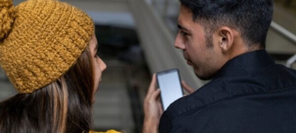 Dos personas viendo un teléfono Claro.