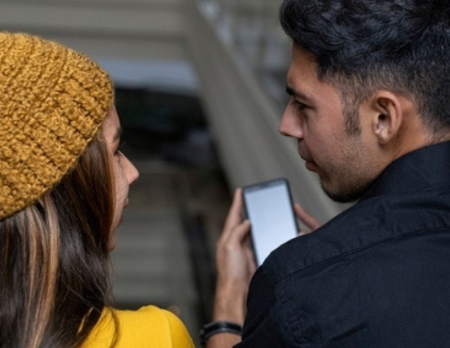 Dos personas viendo un teléfono Claro.