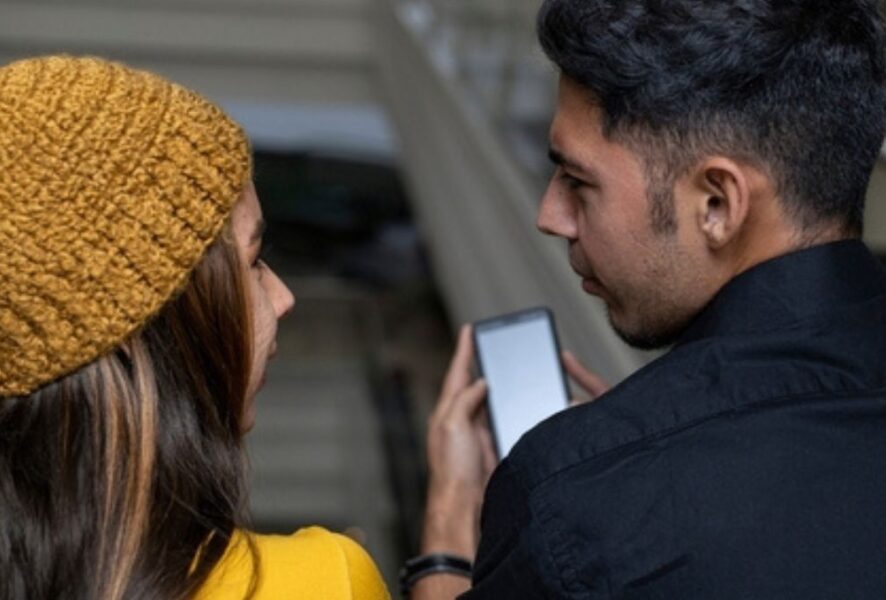 Dos personas viendo un teléfono Claro.