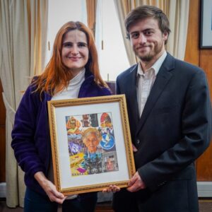 Emilia Ríos, exalcaldesa de la Municipalidad de Ñuñoa y Felipe Carvajal posando con cuadro de Inés Erazo, vecina ilustre de Ñuñoa.
