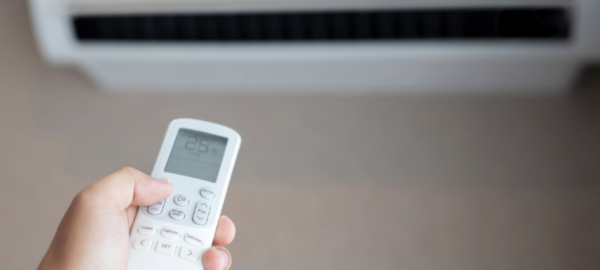 Foto de una persona manipulando a través del control un aire acondicionado inverter.