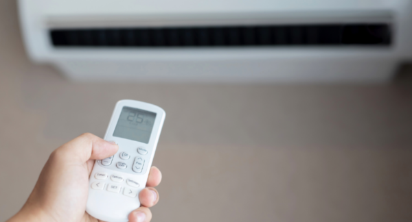 Foto de una persona manipulando a través del control un aire acondicionado inverter.