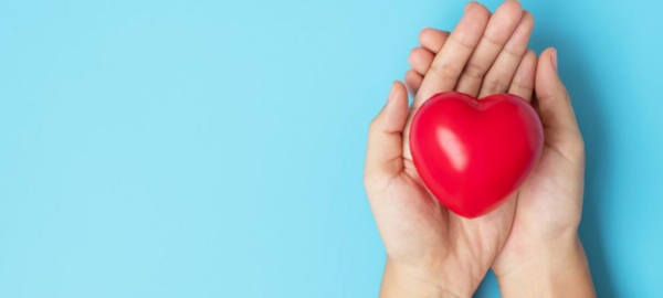 Foto de una mujer sosteniendo un corazón para prevenir los riesgos cardiovasculares en mujeres.