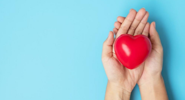 Foto de una mujer sosteniendo un corazón para prevenir los riesgos cardiovasculares en mujeres.