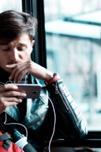 Persona escuchando con audífonos en el metro con el celular en la mano