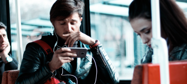 Persona escuchando con audífonos en el metro con el celular en la mano