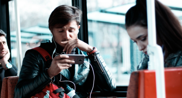 Persona escuchando con audífonos en el metro con el celular en la mano