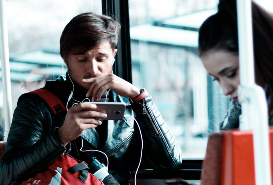 Persona escuchando con audífonos en el metro con el celular en la mano